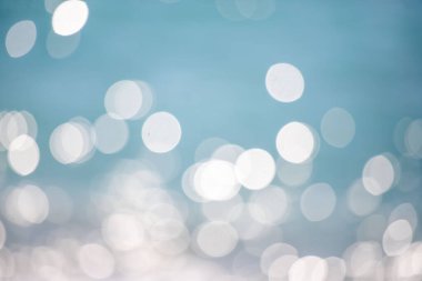 Görüntü bulanık mavi bir zemin ve etrafa dağılmış beyaz daireler. Daireler farklı boyutlarda ve havada süzülüyor gibi görünüyor. Sahne rüya gibi ve ruhani.