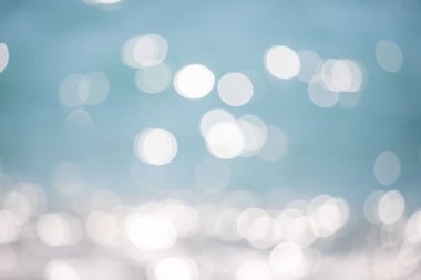 Görüntü bulanık mavi bir zemin ve etrafa dağılmış beyaz daireler. Daireler farklı boyutlarda ve havada süzülüyor gibi görünüyor. Sahne rüya gibi ve ruhani.