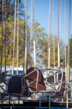 Kahverengi şapkalı bir dizi salıncak. Şapka kullanılmayan bir sandalyenin üzerinde.