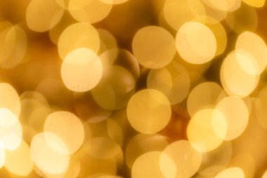 Görüntü bulanık, sarı arkaplan ve küçük daireler. Daireler farklı boyutlarda ve birbiriyle çakışıyor gibi görünüyor. Genel etkisi bir hareket ve enerji duygusu.