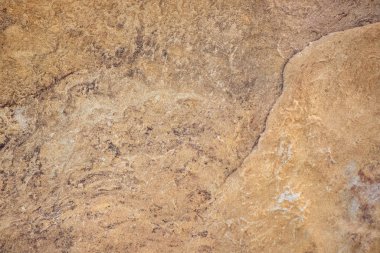 Kaba bir dokusu olan kahverengi bir yüzey. Yüzey taştan yapılmıştır ve kumlu bir görünüşü vardır.