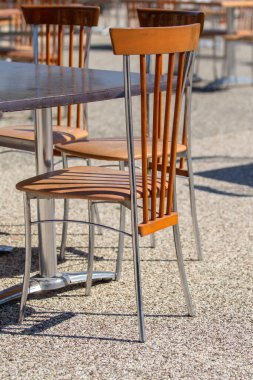 Bir masanın önünde ahşap bir sandalye oturuyor. Sandalye boş ve masa boş.