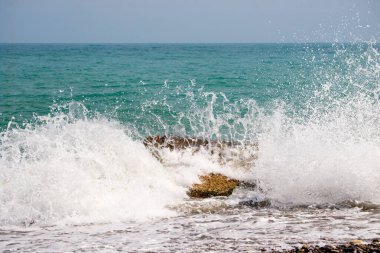 Okyanus sakin ve su mavi. Dalgalar küçük ve naziktir. Gökyüzü açık ve parlak