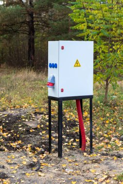 Üzerinde sarı işaret olan beyaz bir kutu. Kutu arka planda ağaçlarla dolu bir alanda.