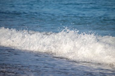 Okyanus dalgaları kıyıya çarpıyor, güzel ve rahatlatıcı bir manzara yaratıyor. Su koyu mavi bir renktir ve plajdaki kayalar manzaraya biraz doku katar.