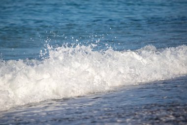 Okyanus dalgaları kıyıya çarpıyor, güzel ve rahatlatıcı bir manzara yaratıyor. Su koyu mavi bir renktir ve plajdaki kayalar manzaraya biraz doku katar.
