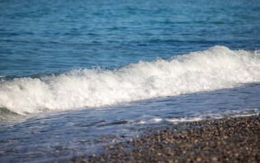 Okyanus dalgaları kıyıya çarpıyor, güzel ve rahatlatıcı bir manzara yaratıyor. Su koyu mavi bir renktir ve plajdaki kayalar manzaraya biraz doku katar.