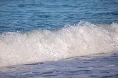 Okyanus dalgaları kıyıya çarpıyor, güzel ve rahatlatıcı bir manzara yaratıyor. Su koyu mavi bir renktir ve plajdaki kayalar manzaraya biraz doku katar.