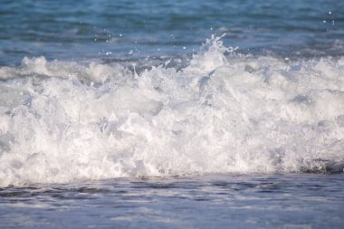 Okyanus dalgaları kıyıya çarpıyor, güzel ve rahatlatıcı bir manzara yaratıyor. Su koyu mavi bir renktir ve plajdaki kayalar manzaraya biraz doku katar.