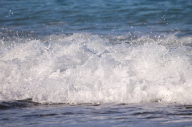 Okyanus dalgaları kıyıya çarpıyor, güzel ve rahatlatıcı bir manzara yaratıyor. Su koyu mavi bir renktir ve plajdaki kayalar manzaraya biraz doku katar.
