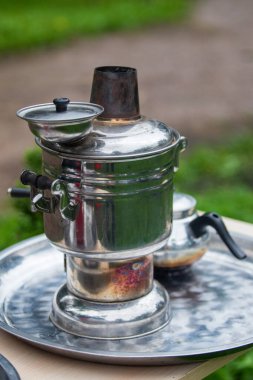 Bir çaydanlık ve küçük bir fincanın yanındaki tepside gümüş bir çaydanlık bulunur. Çaydanlık bir kapakla kaplı ve ağzı var. Rahatlama ve rahatlama kavramı, çaydanlık gibi.