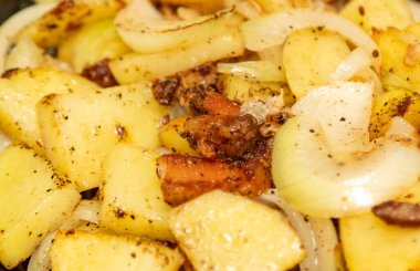 A plate of food with potatoes, onions, and bacon. The potatoes are seasoned with salt and pepper
