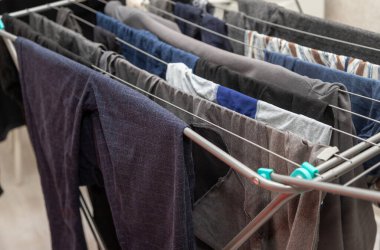 A clothesline with clothes hanging on it, including a pair of blue pants. The clothesline is outdoors and the clothes are drying in the sun