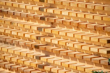A stack of wood planks with a lot of shadowing. The wood is brown and the shadows are dark
