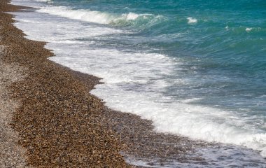 Okyanus sakin ve sahil kayalık. Su mavi ve dalgalar küçük.