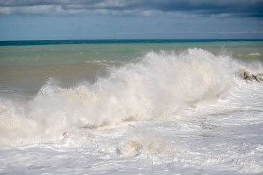 Okyanus dalgalı ve dalgalar yüksek. Su beyaz ve gökyüzü mavi.