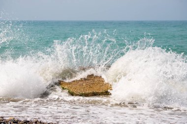 Okyanus bir kayaya çarpıyor, güçlü ve dinamik bir manzara yaratıyor. Su beyaz ve köpüklü ve kaya yosunlarla kaplı. Sahne, enerji ve hareketlerden biridir.