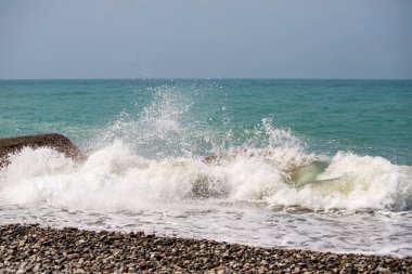 Okyanus sakin ve dalgalar küçük. Su mavinin güzel bir tonu. Gökyüzü açık ve güneş parlıyor.