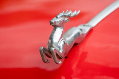 Kırmızı arka planda gümüş bir geyik var. Geyik havaya sıçrıyor ve görüntüde neşeli ve kaprisli bir hava var.