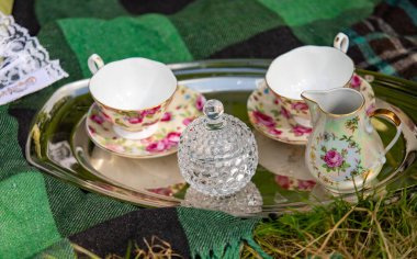 A tray with two cups and a pitcher of water. The cups are white and pink and the pitcher is green and white