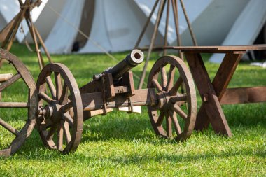 Tahta bir masanın yanındaki çimen tarlasında bir top duruyor. Sahne huzurlu ve sakin, eski moda top sete bir tarih ve nostalji katıyor.