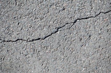 Bir sürü çakıl olan çatlak ve bozuk bir yol. Yol bakımsız ve araba kullanmak için güvenli değil.