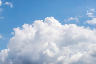 Gökyüzünde mavi arkaplanı olan büyük bir bulut. Bulut beyaz ve kabarık. Gökyüzü açık ve parlak