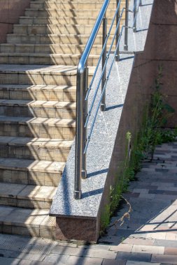 A staircase with a railing and a shadow cast on the steps. The railing is made of metal and is located on the side of the stairs