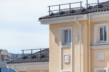 Beyaz çatılı ve siyah çatılı bir bina. Binanın bir sürü penceresi var ve pencereler bir çok doğal ışığın içeri girmesini sağlayacak şekilde düzenlenmiş.