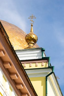 A gold dome with a cross on top of it is on top of a building. The dome is located on the roof of the building