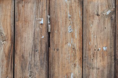 The image is of a wooden surface with a lot of texture and a few holes. The wood appears to be old and weathered, giving the impression of a rustic or antique feel
