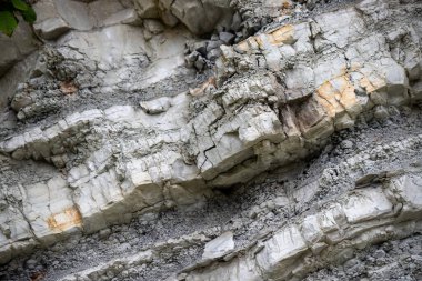 A rock wall with a lot of cracks and holes. The cracks are deep and the holes are small