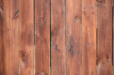 A wooden fence with a grainy texture and a rustic appearance. The fence is made of wood and has a natural, earthy feel to it