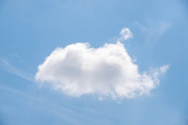 A large white cloud in a blue sky. The cloud is shaped like a heart. The sky is clear and bright, with no signs of rain or storms. The cloud is the main focus of the image