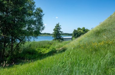 A lush green hillside with a body of water in the background. The scene is peaceful and serene