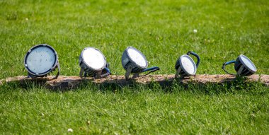 A row of lights are on a wooden log in a grassy field. The lights are all different sizes and colors, creating a vibrant and lively atmosphere. Concept of energy and excitement