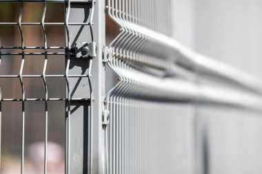 A metal fence with a wire mesh on it. The fence is white and has a silver color