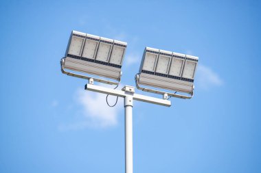 Gökyüzündeki bir direkte iki büyük ışık var. Gökyüzü mavi ve berrak. Işıklar güneşli bir günde