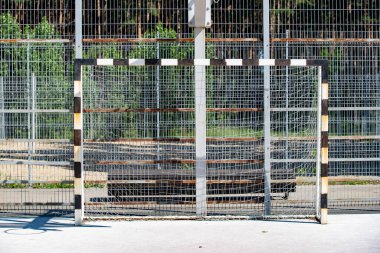 Siyah beyaz çizgili direkli bir futbol golü. Amaç boş. Çit metal ve ahşaptan yapılmıştır.