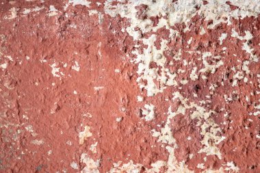 Kırmızı ve beyaz desenli bir duvar. Duvar eski ve pürüzlü bir dokusu var. Kırmızı ve beyaz desen solmuş ve yıpranmış. Duvara bir yaş ve tarih hissi veriyor.