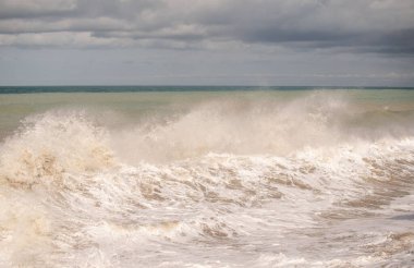 The ocean is rough and the waves are high. The sky is cloudy and the water is white