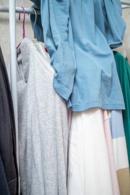 Üzerinde mavi tişört ve beyaz gömlek olan bir elbise askısı..