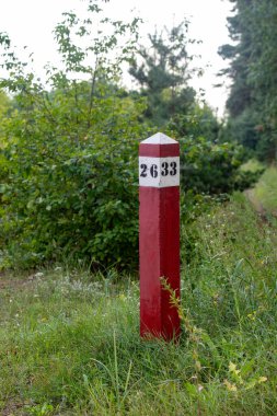 Üzerinde 633 yazan kırmızı ve beyaz bir tabela. İşaret arka planda ağaçlar olan çimenli bir alanda.