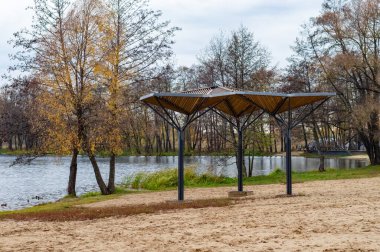 Gölü ve köşkü olan bir park. Çadırda kimse yok. Ağaçlar çıplak ve gökyüzü bulutlu.