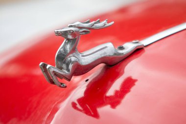 Kırmızı bir arabada gümüş bir geyik var. Geyik sağa bakıyor.