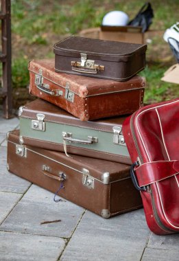 Üstünde kırmızı olan bir yığın eski bavul. Bavullar eski ve yıpranmış, ve en göze çarpanı kırmızı olan. Sahne nostalji hissi veriyor.