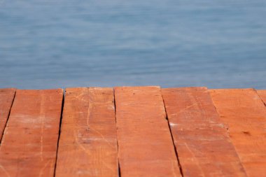 Su manzaralı ahşap bir tahta kaldırım. Su mavi ve sakindir. Tahta kaldırım tahtadan yapılmıştır ve suyun üzerinde yüksektir.