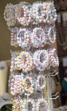 Farklı renk ve tasarımlara sahip bir bilezik gösterisi. Bilezikler beyaz bir askıda.