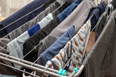 Pantolon ve gömlekler de dahil olmak üzere çeşitli kıyafetlerin asılı olduğu bir çamaşır ipi. Elbiseler güneşte kuruyor.