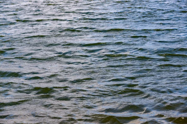 The water is calm and still. The sky is clear and bright. The water is blue and has no ripples